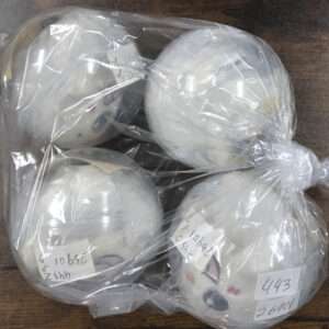 Bag containing four white round ornaments with cartoon faces drawn on them and small handwritten notes attached.
