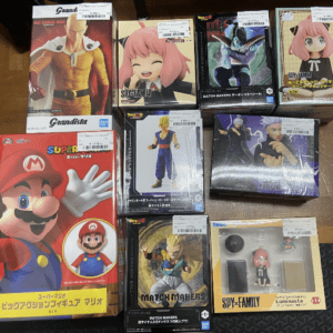 Assorted boxed action figures on a wooden floor, including Mario and anime/game character figures.
