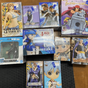 A collection of boxed anime figures on a wooden floor, featuring colorful character boxes arranged together.