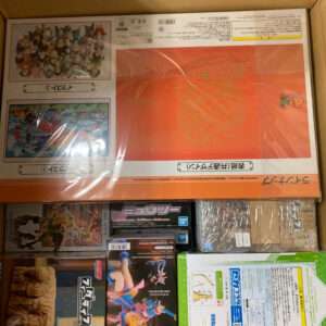 Box containing multiple anime figure boxes, including a large orange box on top and smaller character figures at the bottom inside a shipping carton.