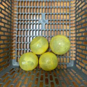 Four yellow translucent plastic balls placed in a gray perforated basket.