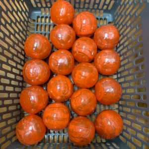 Basket filled with multiple orange plastic-wrapped spheres in a shopping basket.