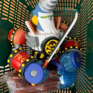 Plastic pirate-robot toy with a silver conical hat, white beard, yellow ear guards, and a curved sword in a green basket; colorful disks and limbs around it.