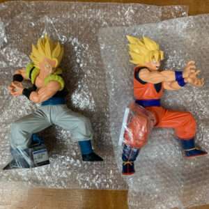 Two Dragon Ball Z action figures in dynamic fighting poses, placed on bubble wrap (one in green/gray with spiky yellow hair, the other in orange/blue).  Articulos Japan (Post Box Japan)
