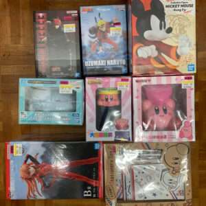 Assorted boxed anime and video game figures on a wooden floor, including Naruto, Mickey Mouse, Kirby, Kirby’s friends, and Evangelion character boxes.