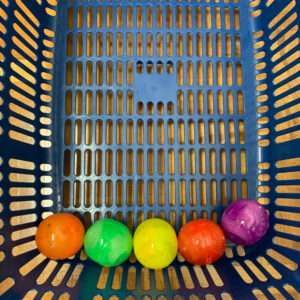 Blue plastic basket bottom with five colorful balls (orange, green, yellow, orange-red, purple) lined along the edge.