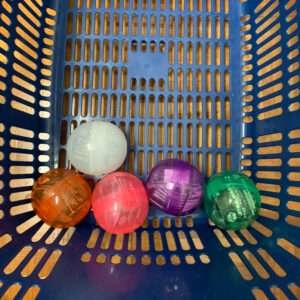 Blue plastic basket with five colorful translucent capsules (orange, white, pink, purple, green) at the bottom.