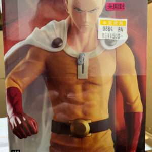 Boxed Grandista SAITAMA One Punch Man action figure: Saitama in yellow suit with white cape, red gloves, and black belt; Bandai branding visible.