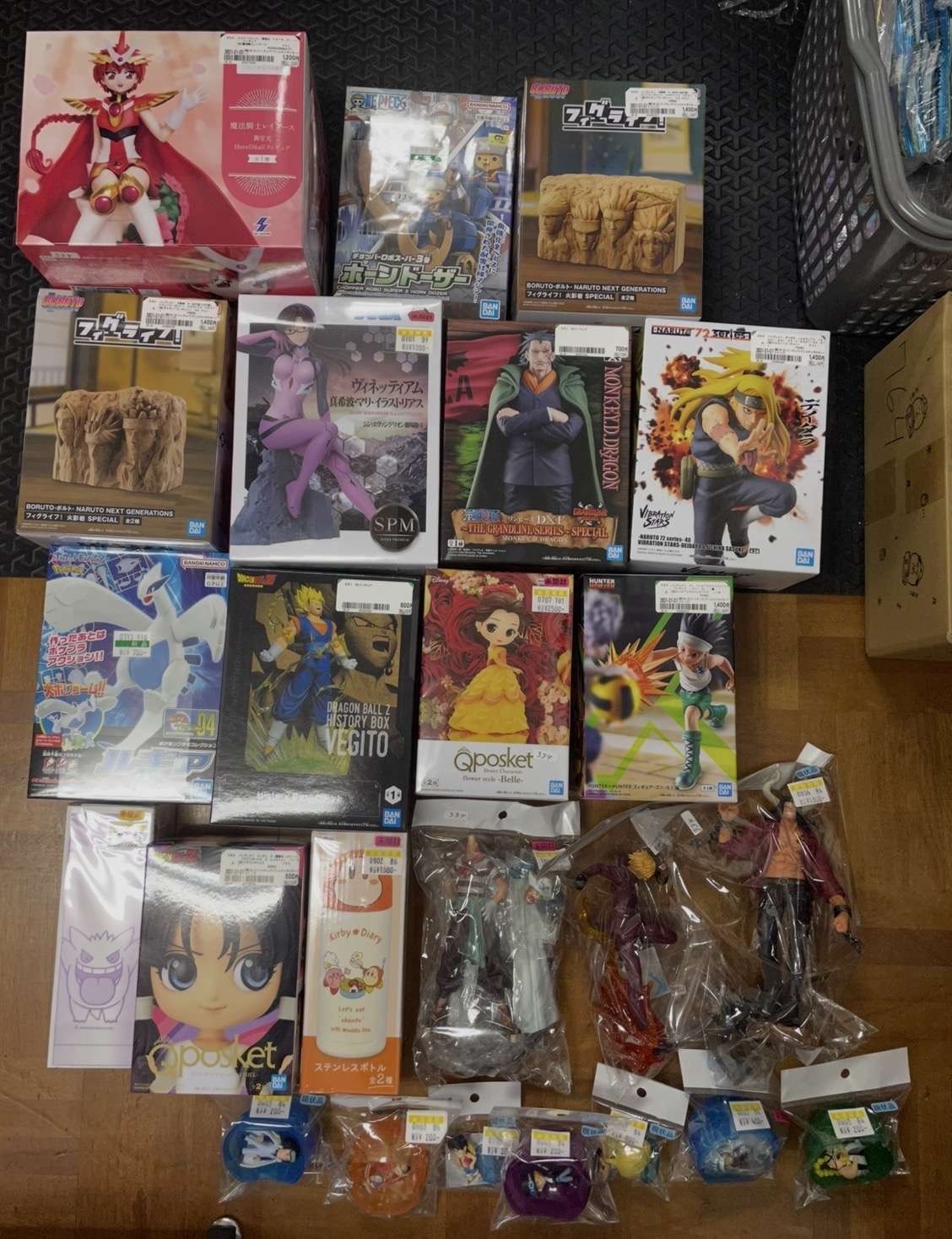 Screenshot - Articulos Japan (post Box Japan) Top-down view of a large assortment of boxed anime figures on a wooden floor, features Naruto, Dragon Ball, One Piece, and Qposket lines still in packaging. Articulos Japan (Post Box Japan)