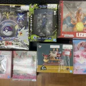 assortment of boxed anime and game figures on a wooden floor, including Pokémon and Sailor Moon items