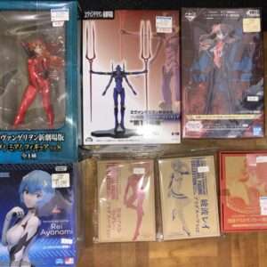 Row of boxed anime figurines on a wooden floor shelf, including Evangelion units and Rei Ayanami figure for sale.  Articulos Japan (Post Box Japan)