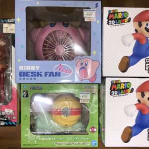 A top-down view of boxed collectible figures on a wooden surface, including Kirby Desk Fan and Super Mario Collection figures.