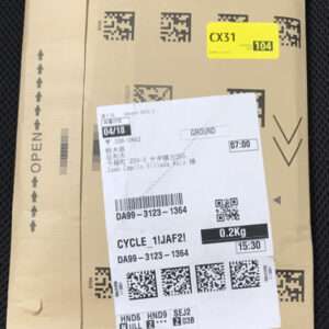 Brown cardboard parcel with a white shipping label and a yellow CX31/104 sticker; label shows barcode, destination details, and weight (0.2 kg).