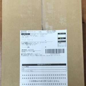 Brown cardboard box with a white shipping label affixed to the front, containing Japanese text and a barcode.