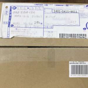 Cardboard box with a blue Japanese shipping label on the top, including handwritten recipient name and a barcodelaiden area.