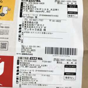 Japanese shipping label with address blocks, barcode, and tracking numbers on a parcel.