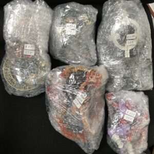 Several plastic-wrapped bundles with white price stickers in yen, laid on a dark surface.