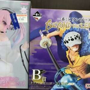 Pair of boxed anime figures: left box shows a pink-haired girl with headphones; right box features a yellow-clad fighter in purple graphics on its cover.