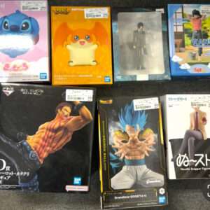 Row of boxed collectible figures on a dark carpet, including Stitch and other anime figures in colorful boxes.