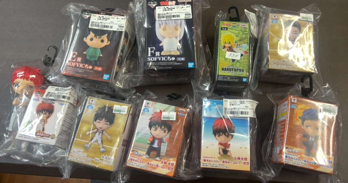Img_9277 - Articulos Japan (post Box Japan) Assorted anime chibi figurines in clear plastic packaging laid on a table, each with price tags visible on the packaging. Articulos Japan (Post Box Japan)