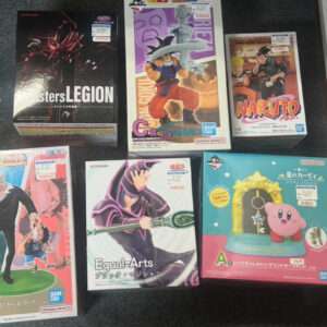 Six boxed anime figurines displayed on a dark carpet: top left is a Konami 'Monsters Legion' box; top middle a Dragon Ball Z statue box with Goku; top right a Naruto box featuring Naruto and another character; bottom left a box with a tall man figure and a child, blue/pink background; bottom middle 'Equal Arts' Black Magician figure box; bottom right a pink Kirby keychain display with a yellow arch and star