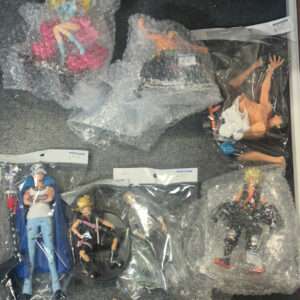 Assorted action figures wrapped in plastic bags and bubble wrap laid out on a gray carpet.