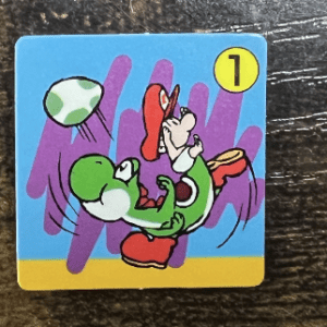 Cartoon green character kicking a ball on a blue card with purple shapes and a yellow bottom edge, featuring a '1' badge in the corner.