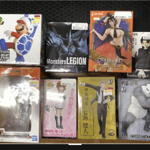 Assorted boxed anime figures arranged on a wooden floor, including Mario, Batman, Overlord, and other characters ready for display or sale