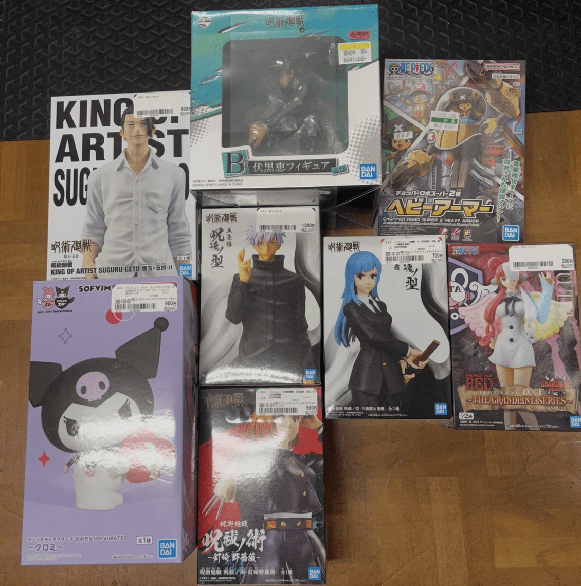 Ver Fotos Recientes 33 - Articulos Japan (post Box Japan) Assorted anime figure boxes arranged on a wooden floor, including a large white-box poster and several character figures from different series. Articulos Japan (Post Box Japan)
