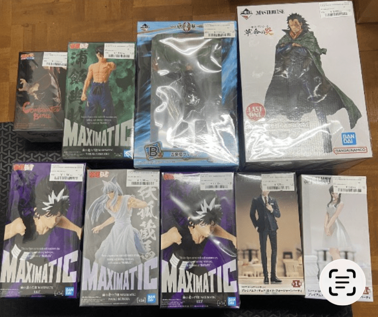 Ver Fotos Recientes - Articulos Japan (post Box Japan) Collection of boxed anime figures laid out on a wooden floor, including Maximatic boxes and a large white-box figure with a cloaked character on the right. Articulos Japan (Post Box Japan)