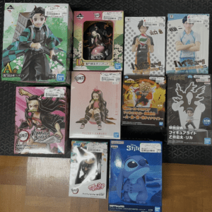 Assorted boxed anime figures displayed on a dark floor mat, featuring colorful character art.
