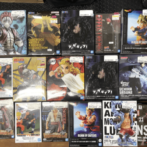 Row of boxed anime action figures (Dragon Ball, Naruto, One Piece) arranged on a wooden floor; colorful packaging shows characters in dynamic poses.