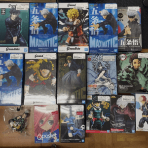 Boxed anime figures on a wooden surface, featuring characters from Naruto, My Hero Academia, and Jujutsu Kaisen in colorful packaging