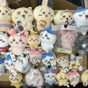 An assortment of cute plush stuffed animals with bunny ears and smiling faces on a display box, in pastel colors.