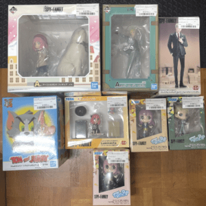 Collection of boxed anime figures on a wooden floor, including SPY×FAMILY characters and Tom and Jerry figurines.