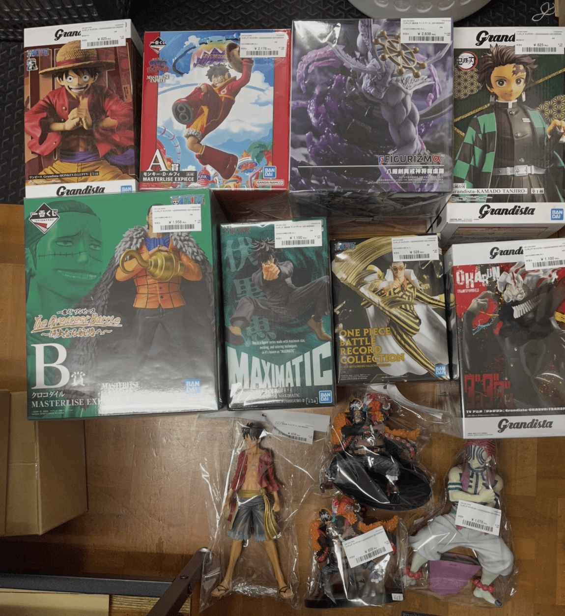 Ver Fotos Recientes 52 - Articulos Japan (post Box Japan) Shelf of anime figure boxes (One Piece, Dragon Ball, and Demon Slayer styles) arranged in two rows with loose figures on the bottom shelf, colorful character boxes facing forward for display. Articulos Japan (Post Box Japan)