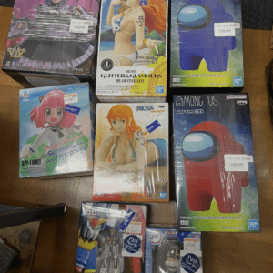 Assortment of anime figure boxes on a wooden table with colorful character art on each box (one Piece, SoFV, etc.).  Articulos Japan (Post Box Japan)