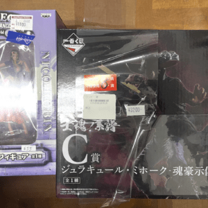 Purple One Piece Nico Robin figure box on the left, flanked by two dark Japanese figure boxes on a wooden surface.