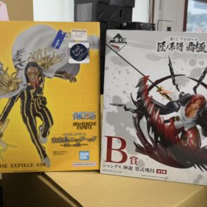 Two boxed One Piece Masterlise EXPiece figures: a yellow box on the left featuring a striped-suit character, and a white box on the right with a red-haired sword-wielding figure.