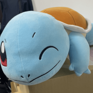 Blue Squirtle plush toy with an orange shell resting on a cardboard box.