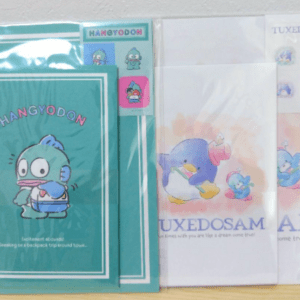 Colorful stationery in plastic sleeves featuring HangyodON character on teal packaging, with additional blue penguin-themed items labeled Tuxedosam on the right.