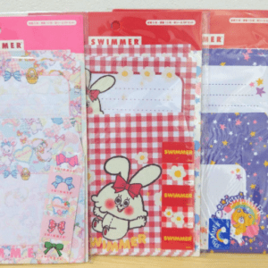 Three Swimmer brand folders in pink bow print, red gingham with a bunny, and purple starry pattern, displayed in packaging.
