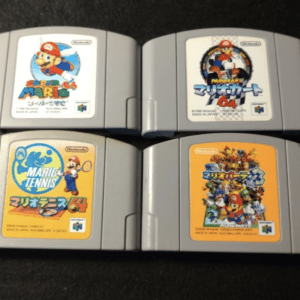Four Nintendo 64 cartridges arranged on a dark surface, featuring Mario games: Super Mario 64, Mario Kart 64, Mario Tennis 64, and Mario Party 2 (orange label).