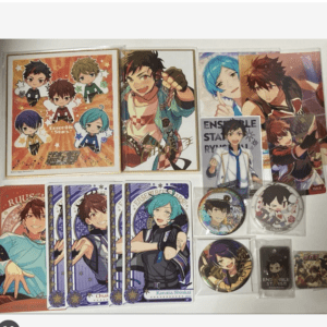 Collection of Ensemble Stars! merchandise laid out on a surface: posters, trading cards, and pins featuring anime characters.