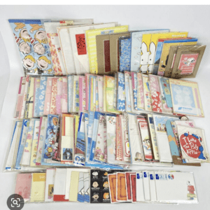 Assorted colorful notebooks, notepads, and greeting cards arranged in rows on a white background.