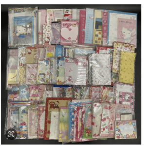 Assorted Hello Kitty-themed stationery in clear bags (notepads, cards, stickers) spread on a dark surface.