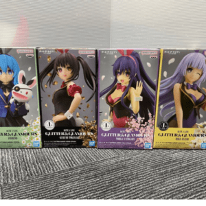 Row of four Glitter & Glamour anime figurine boxes on a carpet, featuring blue-, black-, purple-, and lavender-haired characters.