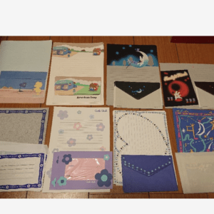 Assorted decorative cards, envelopes, and stationery laid out on a wooden table.