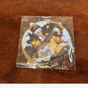 Round enamel pin in clear wrapper featuring a character in a yellow coat holding a colorful rifle, surrounded by clouds and yellow stars.