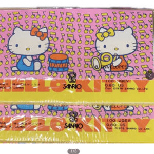 Hello Kitty characters on pink patterned packaging, one drumming and one playing a trumpet, with Sanrio branding.